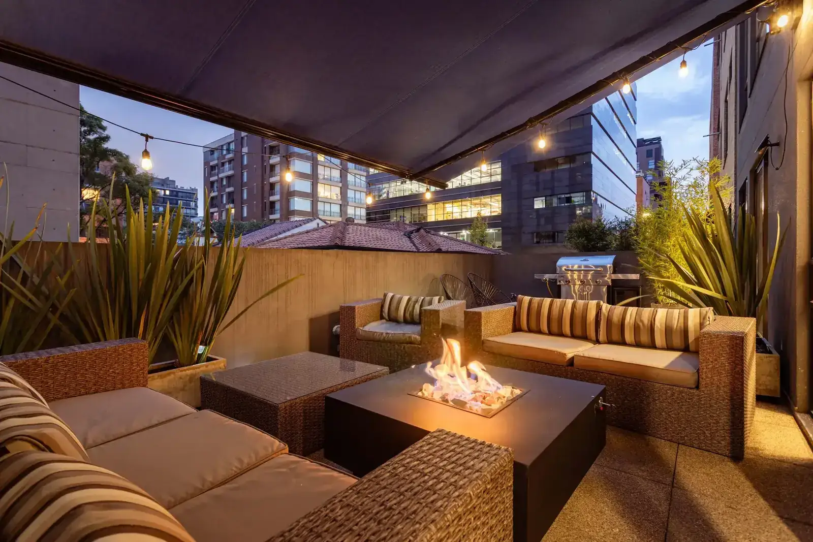 A cozy urban patio setting with elegant furniture and a glowing fire pit during twilight