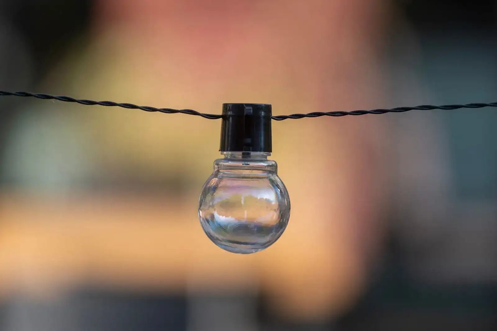 A close-up of a decorative outdoor string light bulb with a blurred background