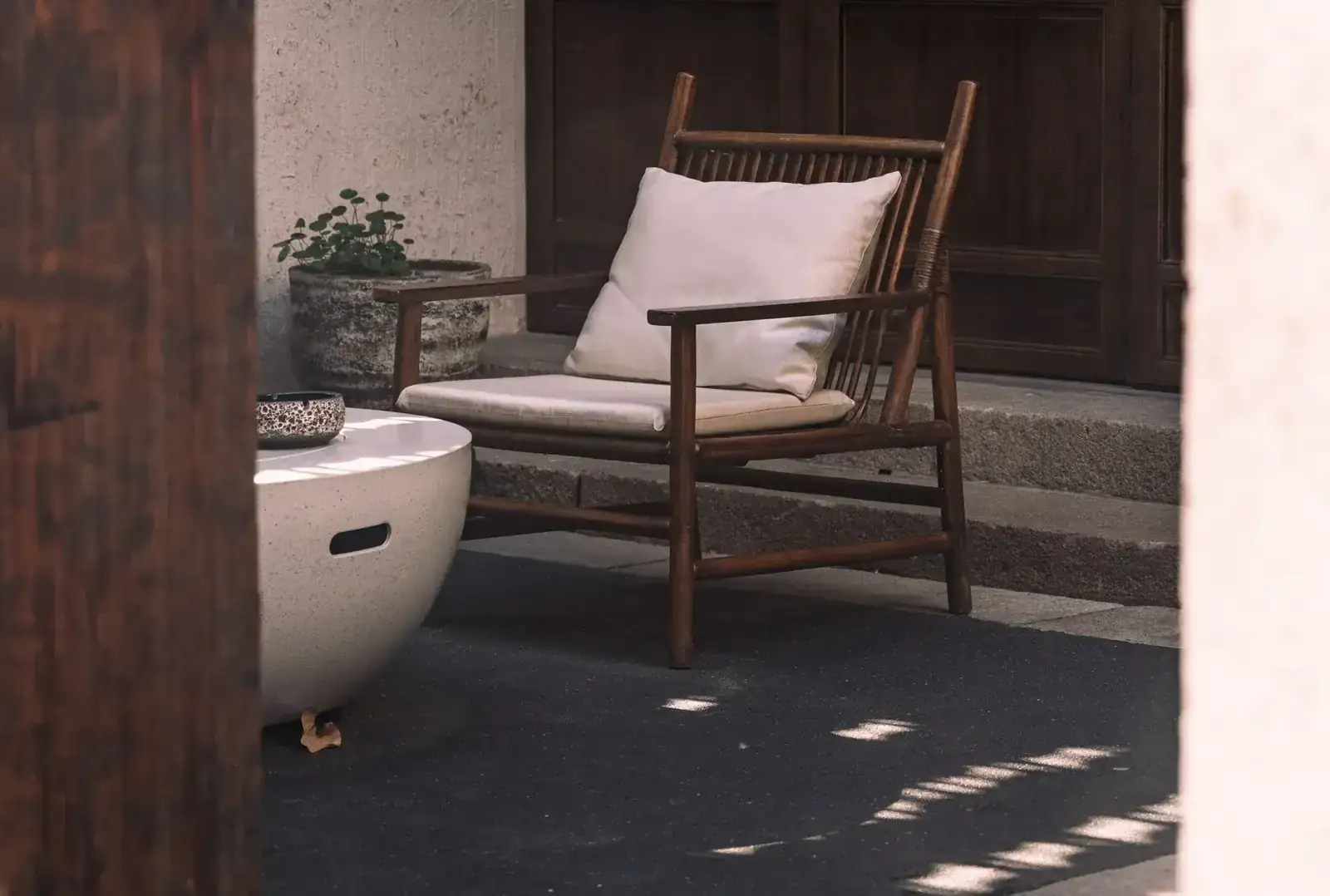 A serene outdoor patio arrangement featuring a wooden chair and a round table under natural light