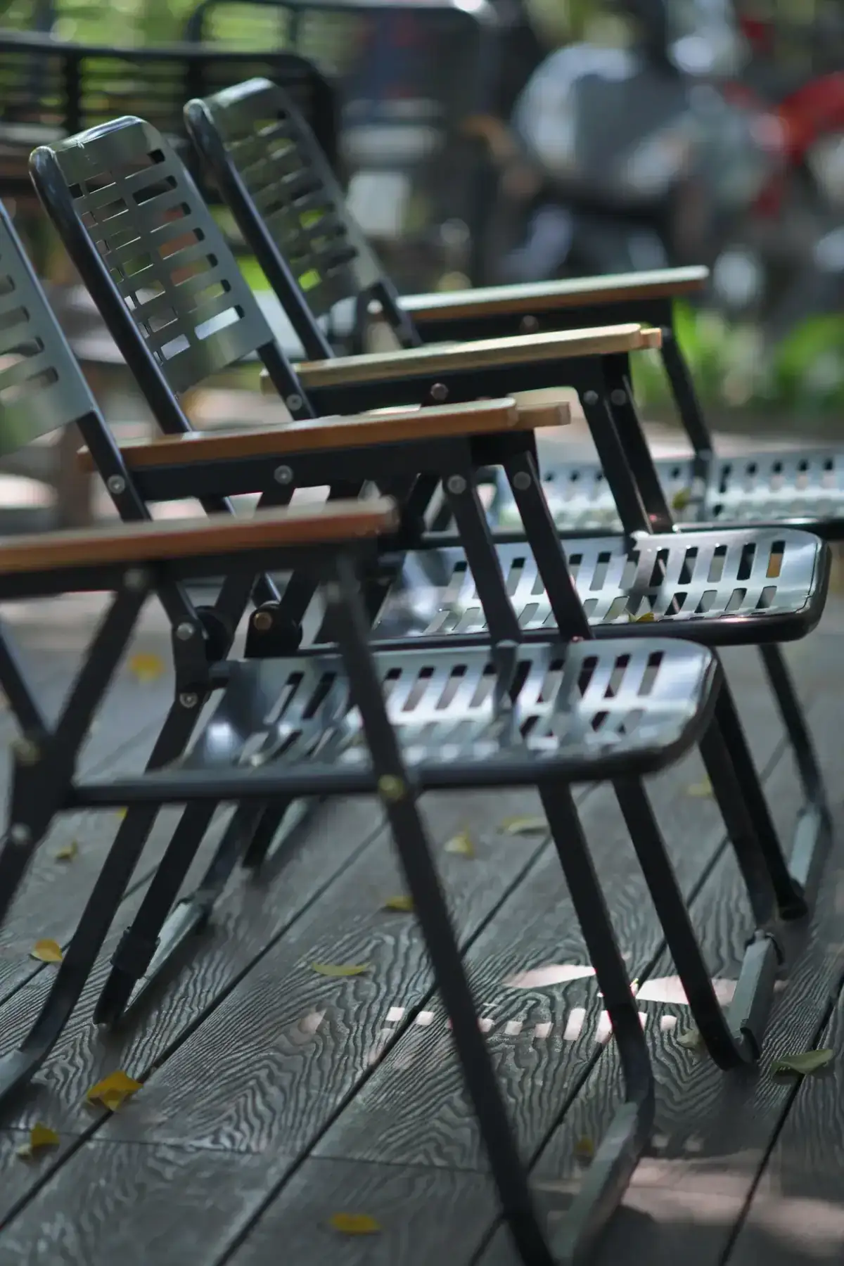 A row of metal chairs line a wooden deck suggesting outdoor seating area