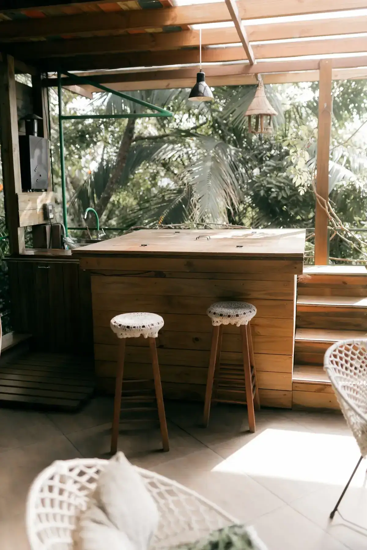Charming outdoor bar with wooden stools and lush greenery, perfect for relaxation