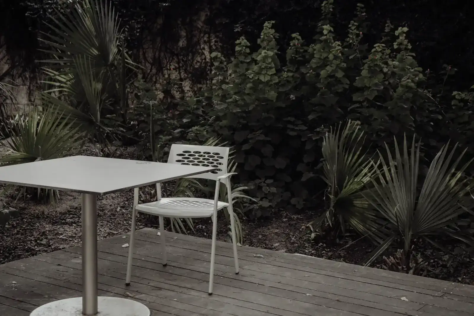 A tranquil outdoor setting with a modern chair and table, surrounded by lush green plants