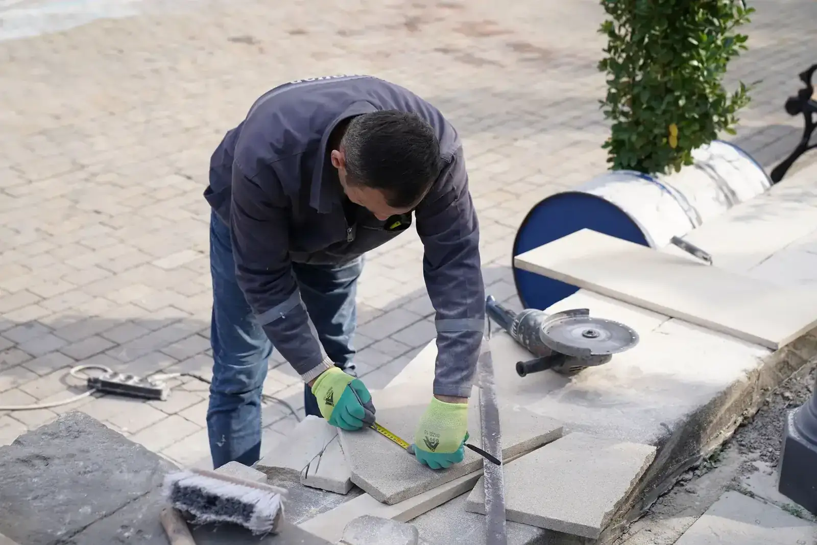A construction worker measuring tiles outdoors with precision tools