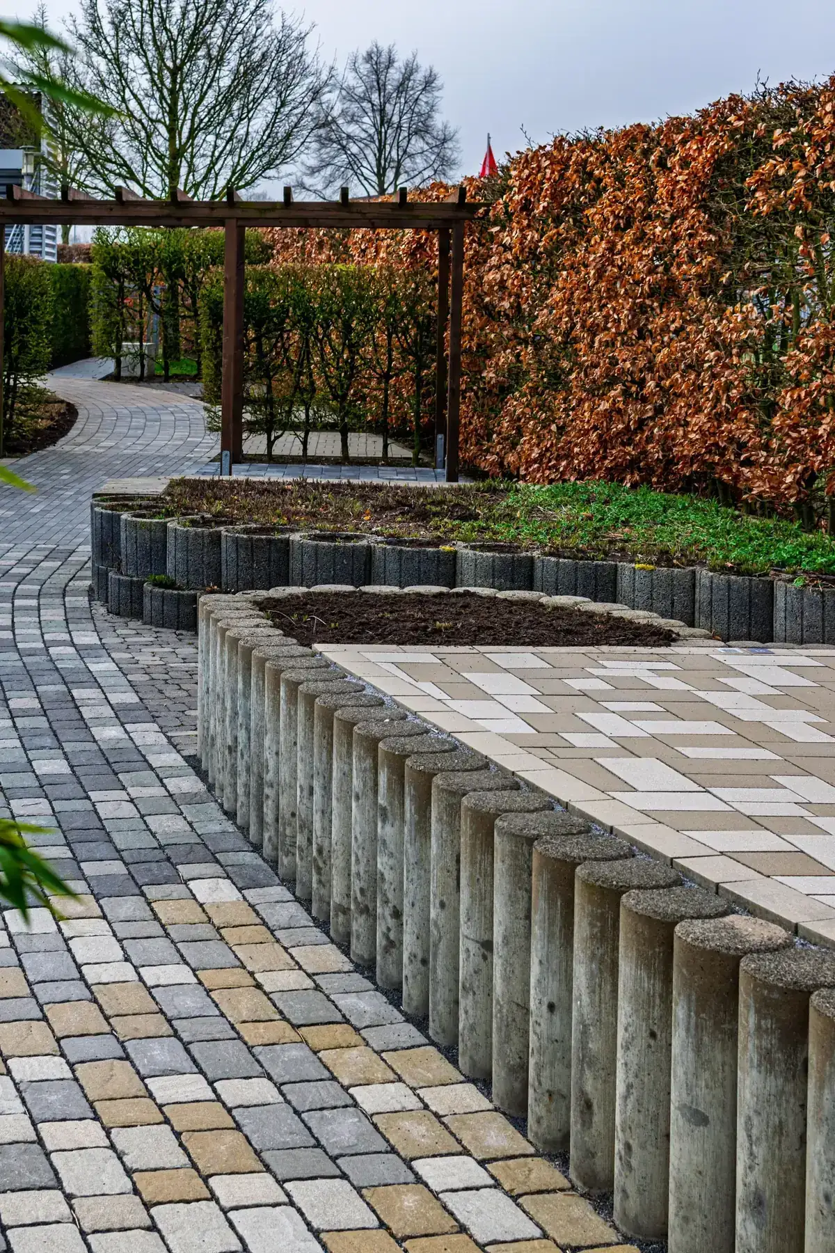 Geometric brick garden path edged by autumn planting