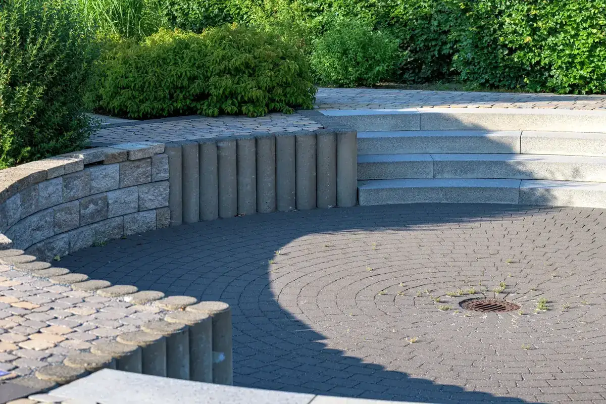 Circular paver patio with a curved retaining wall and broad stone steps