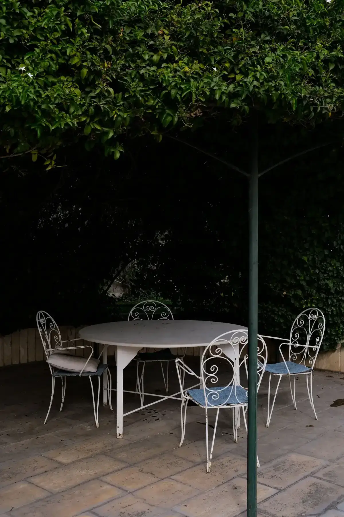 Small shaded patio with vintage-style chairs beneath dense greenery