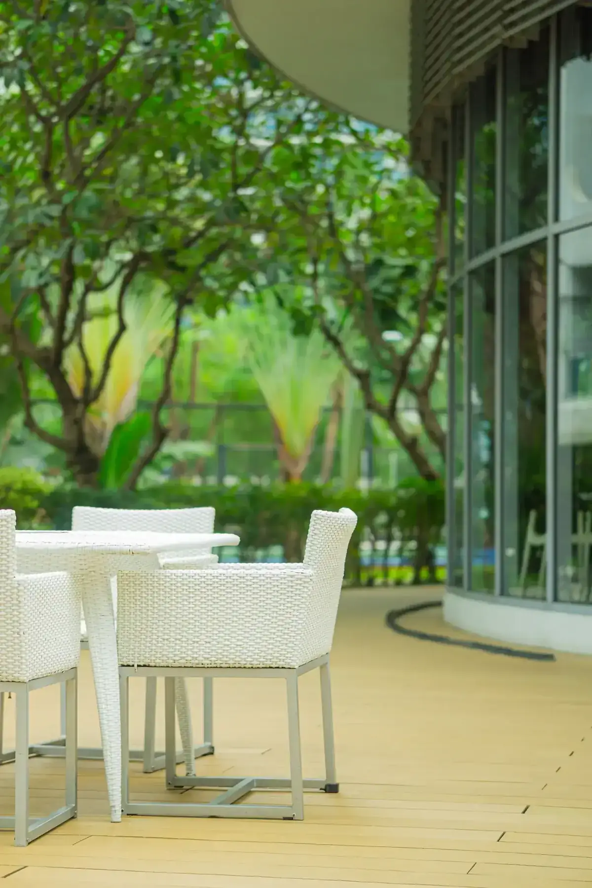 A serene outdoor patio with white wicker furniture surrounded by lush greenery