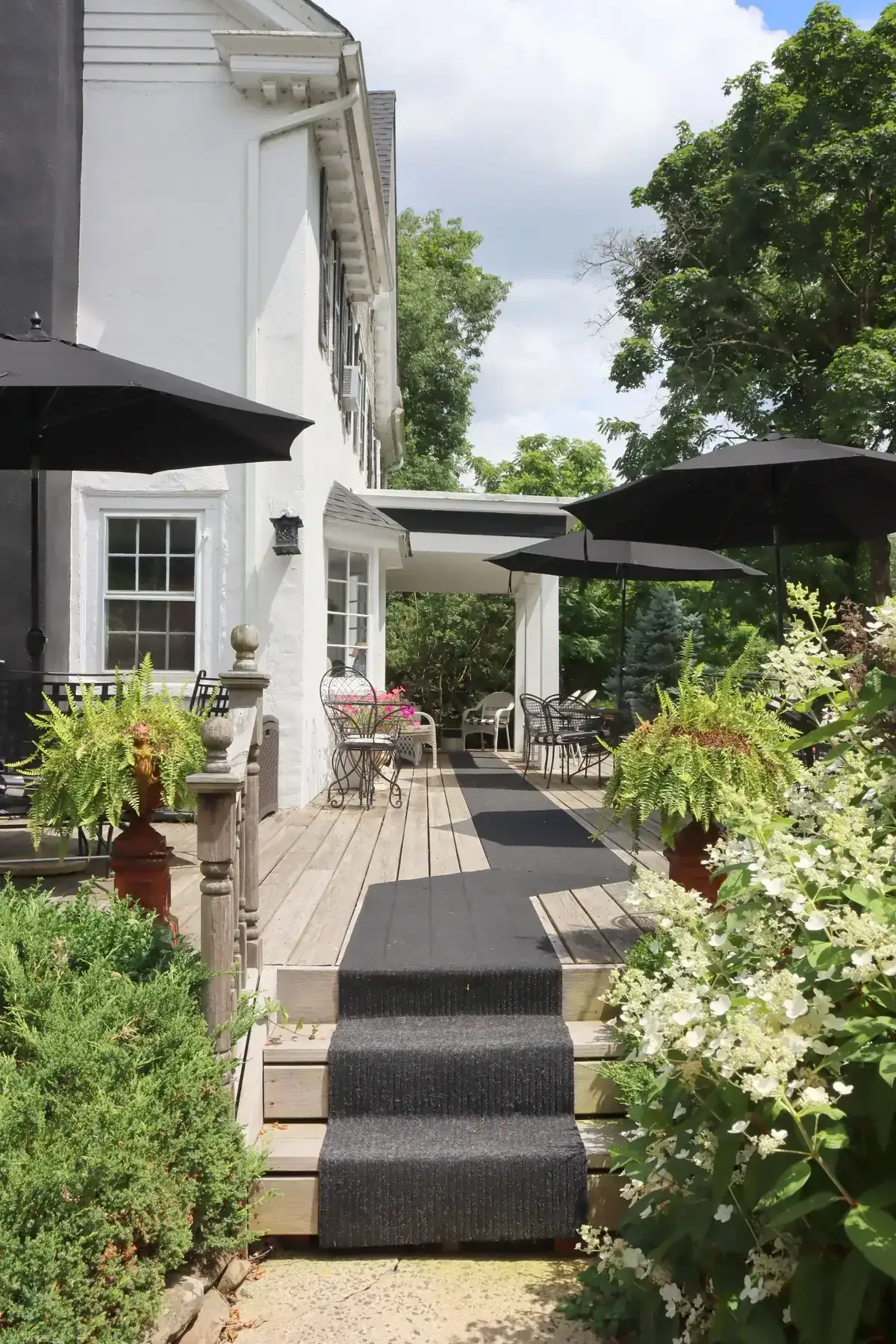 Residential patio with layered greenery and black shade umbrellas