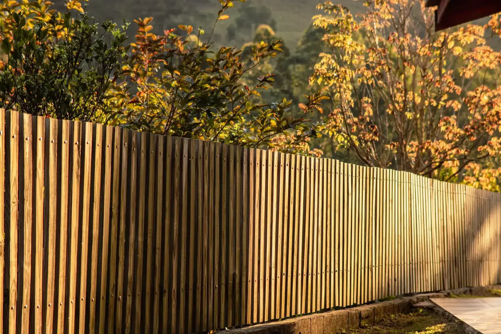 Custom vertical wood fence set against warm autumn foliage