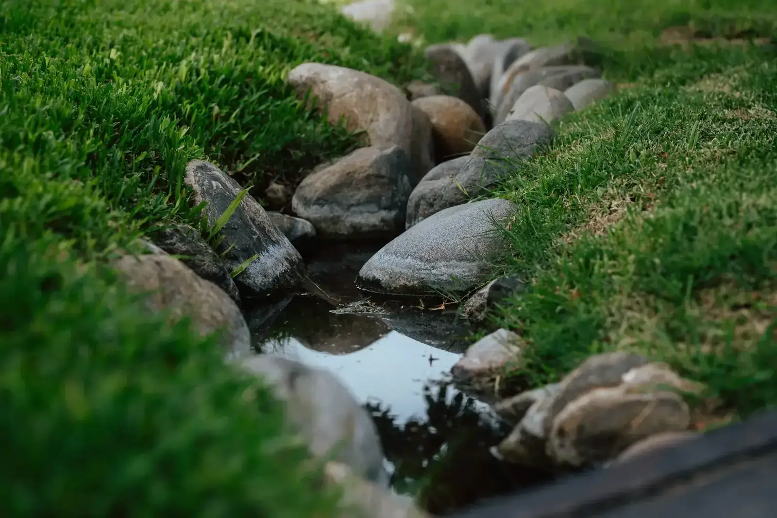 Naturalized drainage stream edged by rocks and lush grass