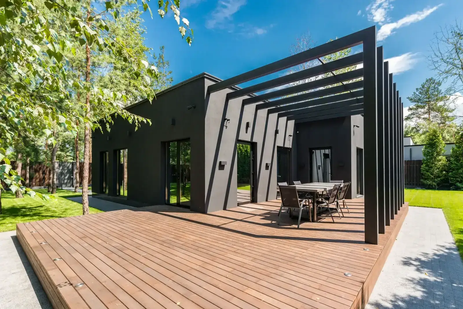Stylish outdoor space with wooden deck and dining set, surrounded by lush greenery