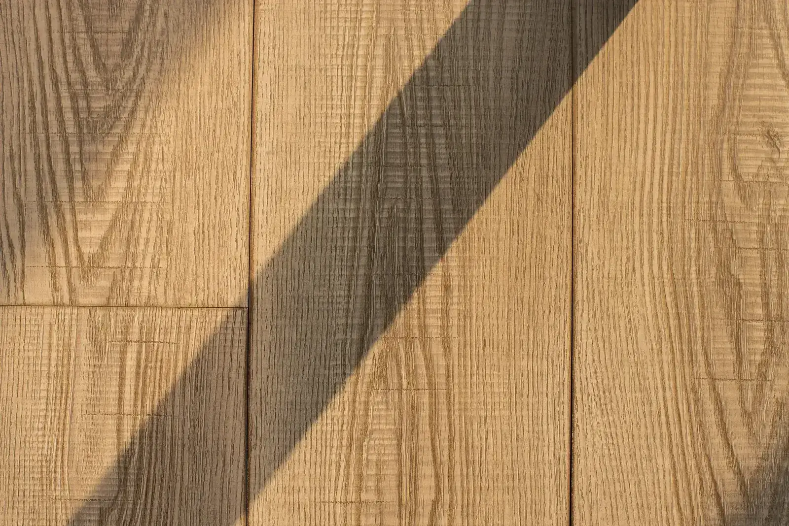 Detailed view of wooden floor planks with a dramatic shadow, showing natural texture