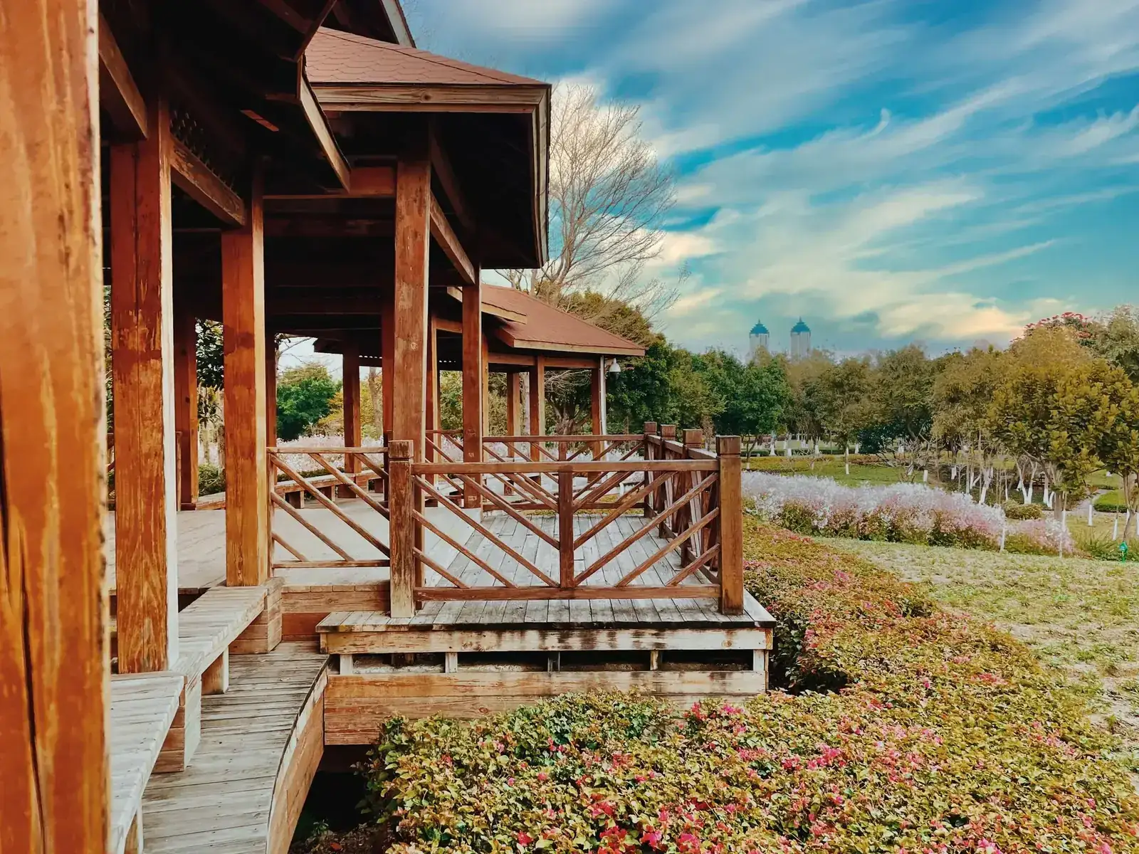 Wooden pavilion with rustic charm in a vibrant park, surrounded by lush greenery and colorful flowers